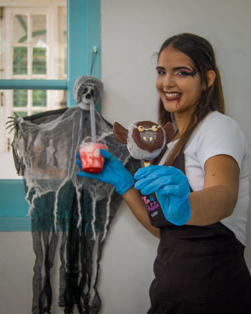 mujer con chocogalleta de forma de murcielago y batido en la manos y esqueleto de fondo