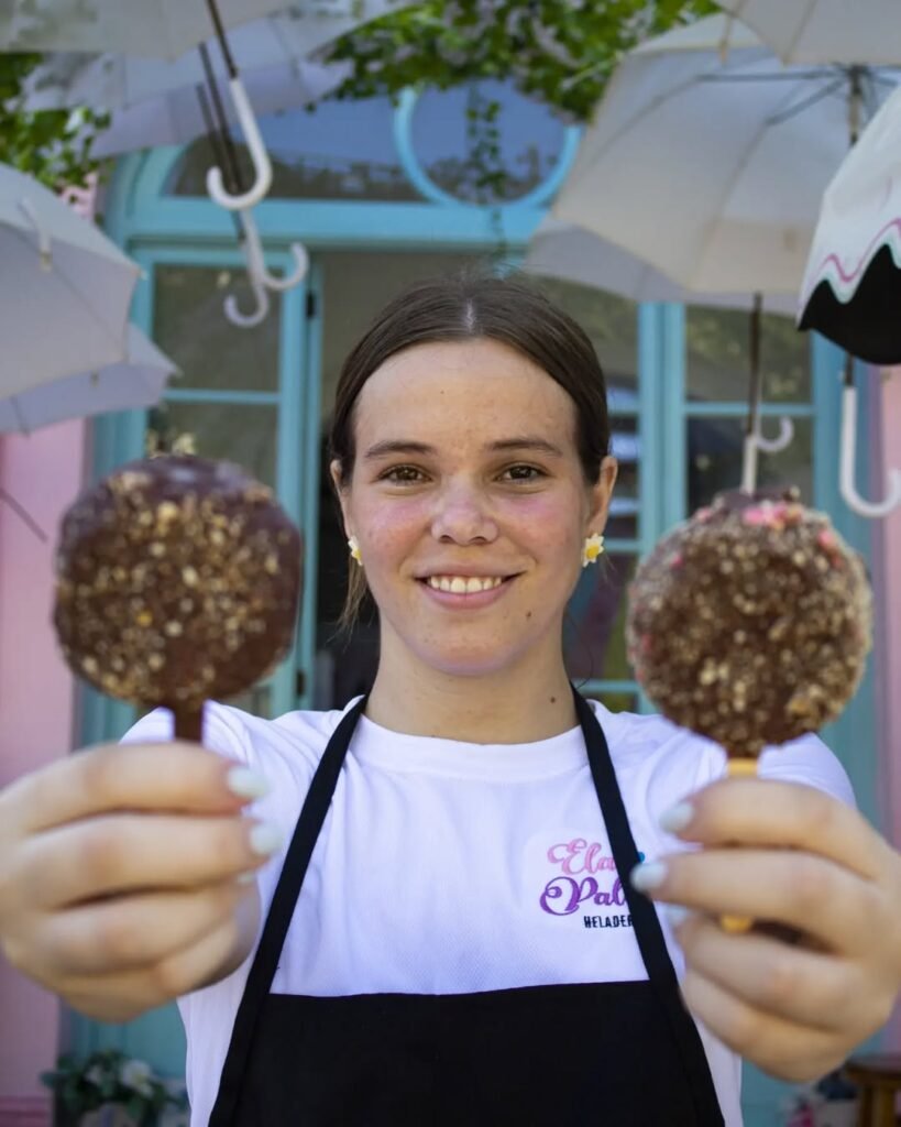 mujer sonriendo en la entrada de la heladería con chocogalletas en sus manos