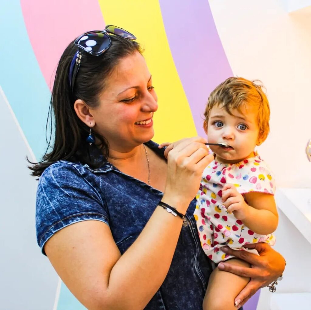 mamá alimentando a su niña con helado